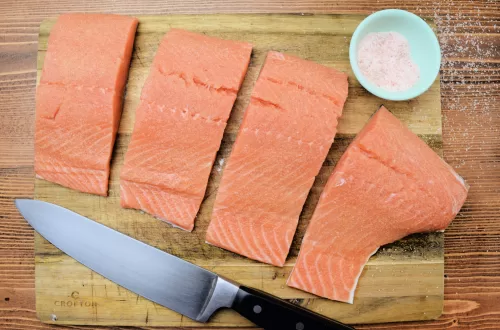 Raw Salmon on a cuttin board for How To Oven Cook Seared Salmon In A Cast Iron Skillet.