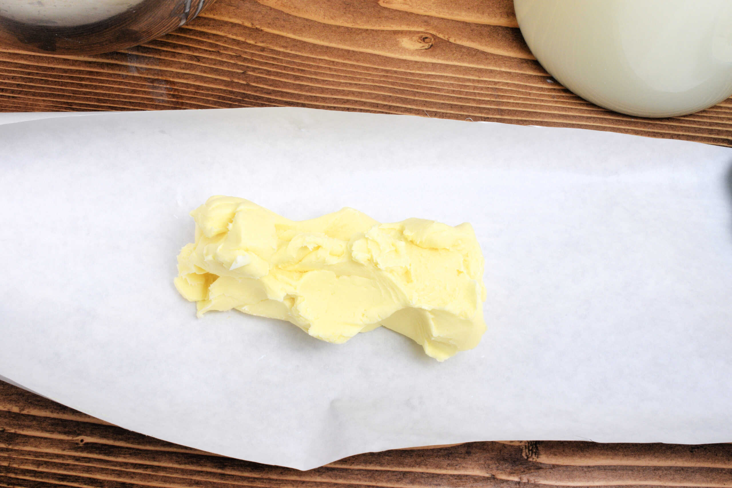 Soft homemade butter placed on parchment paper before being shaped and stored.