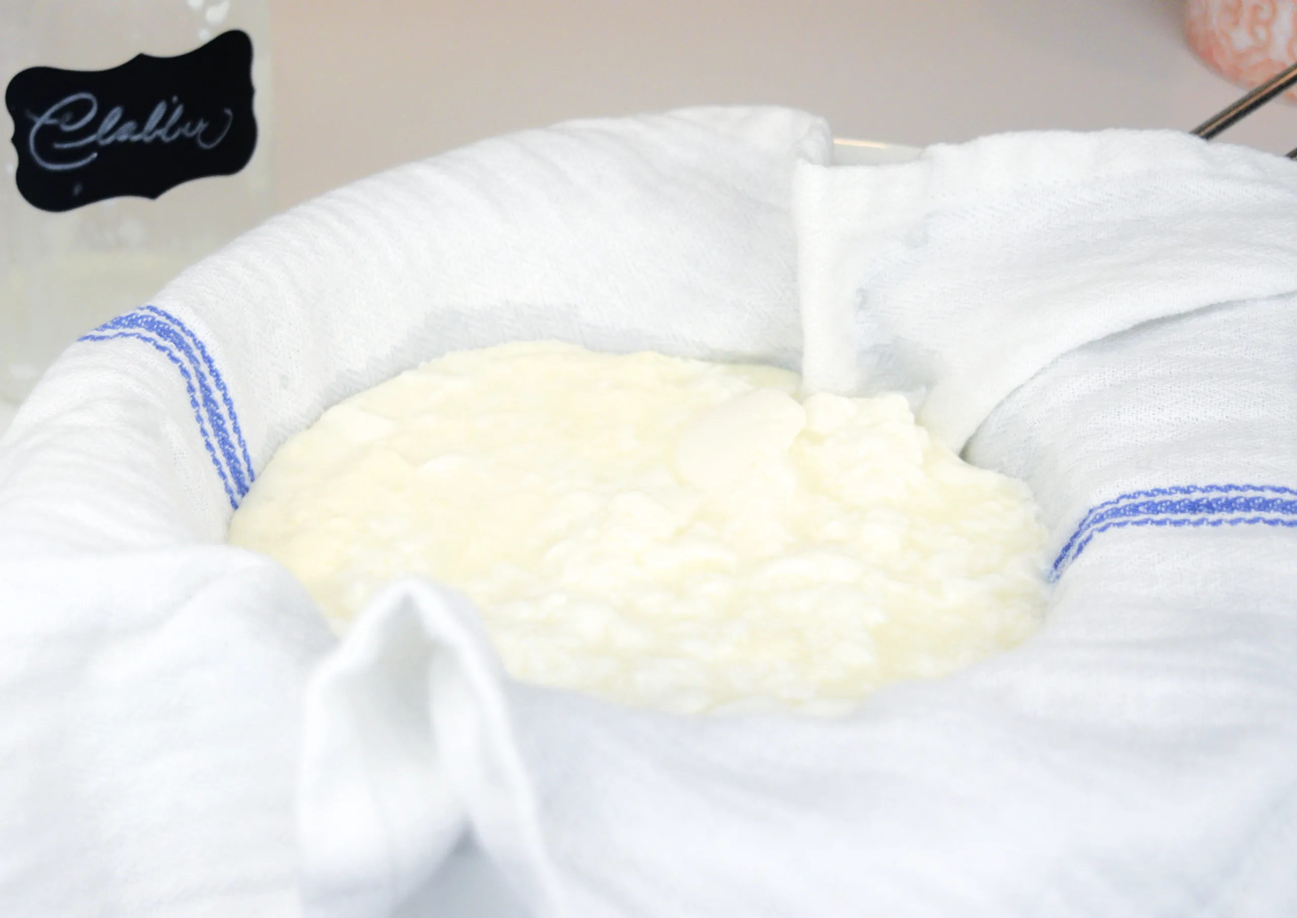 Homemade raw milk clabber straining through a white tea towel to make a thicker texture.