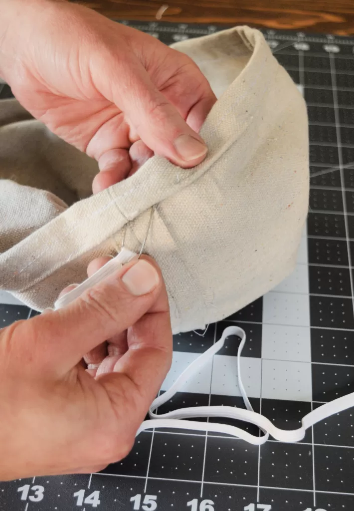 Hands placing elastic into a handmade banneton basket liner.