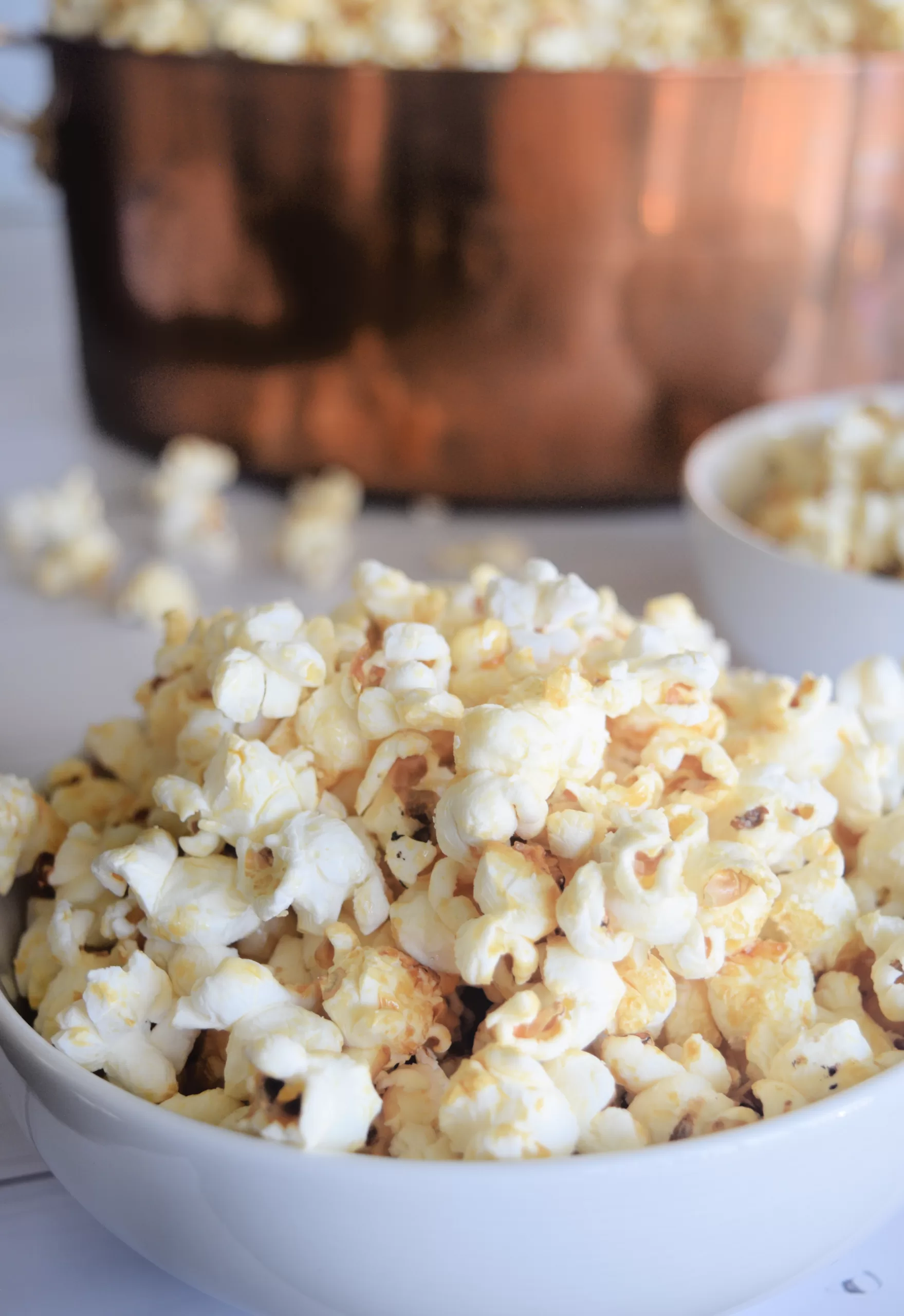 Best Kettle Corn Recipe For a Salty Sweet Snack served in a white bowl on a white countertop.