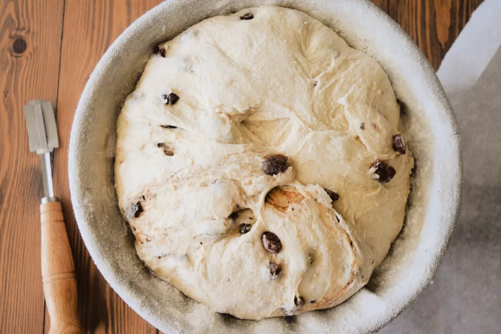 Risen dough in a glass bowl for Best Sourdough Bread Recipe with Almond and Raisins.