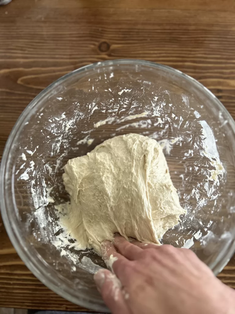 Sourdough being stretched in a glass bowl for Easy Same Day Honey Artisan Sourdough Bread Recipe.
