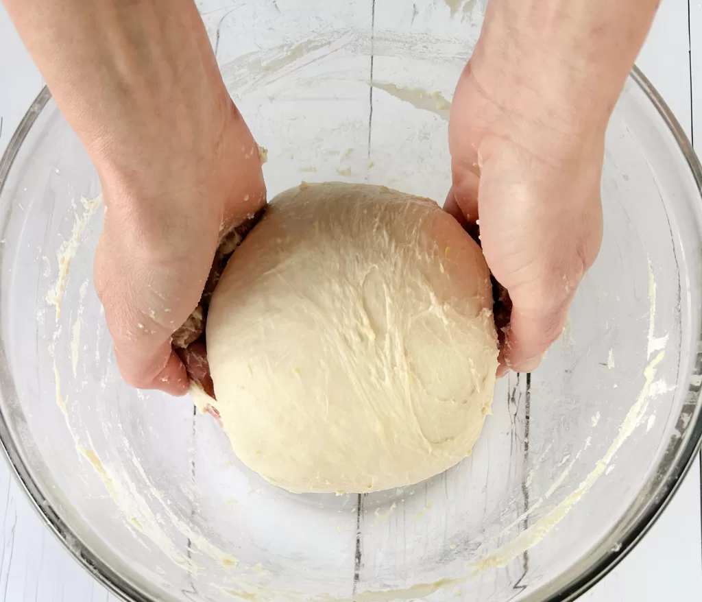 Sourdough dough in a glass bowl being stretched for Simple Lemon Blueberry Sweet Sourdough Bread Recipe.