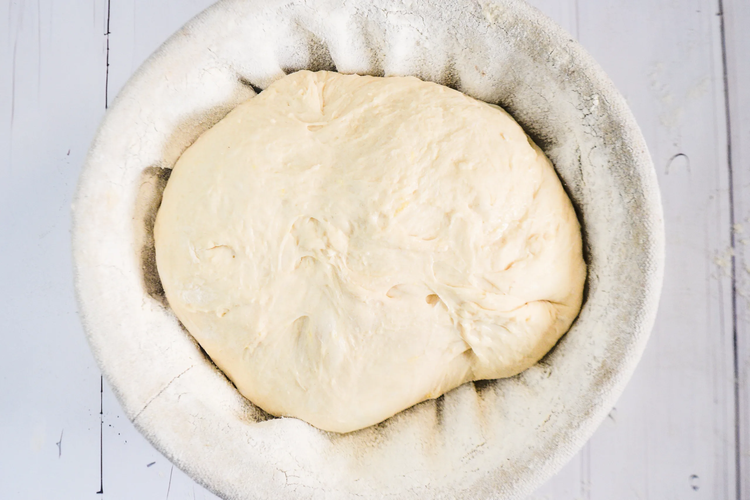 Lemon sourdough dough resting in a floured banneton basket before baking.
