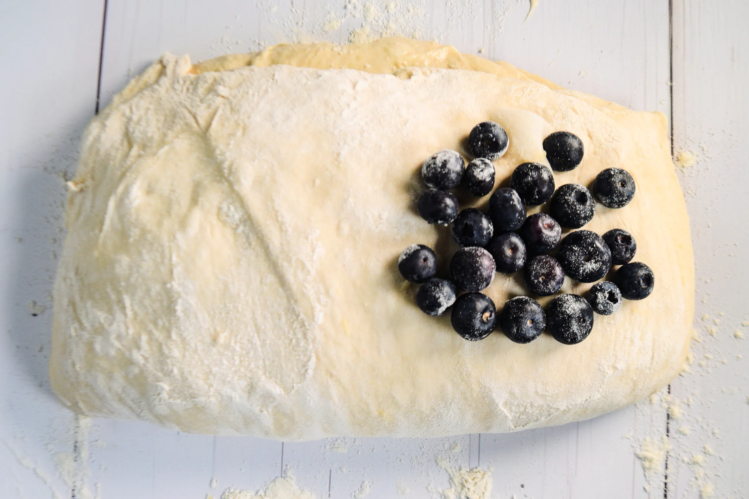 Fresh blueberries placed on one side of stretched sourdough dough for lemon blueberry sweet sourdough bread.