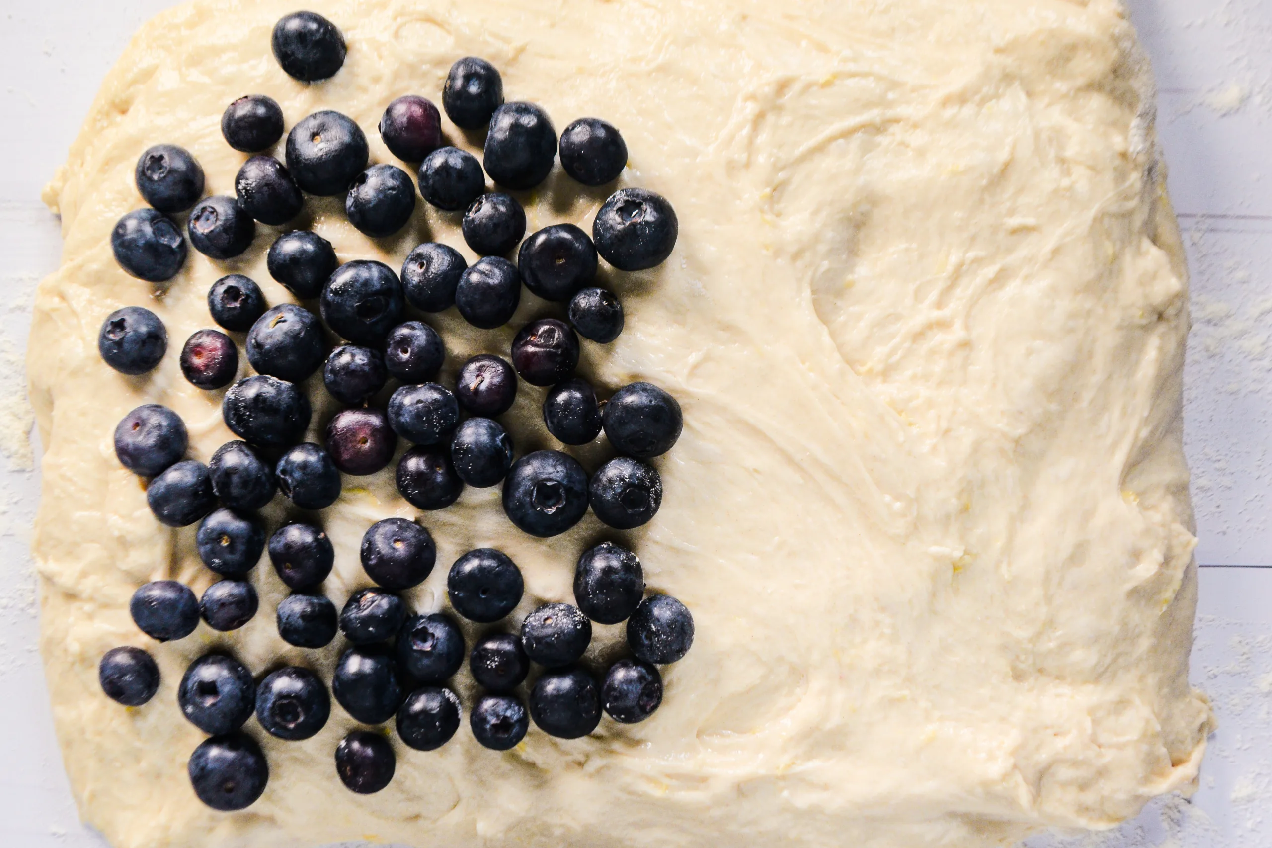 Fresh blueberries spread over stretched sourdough dough before folding and shaping the loaf.