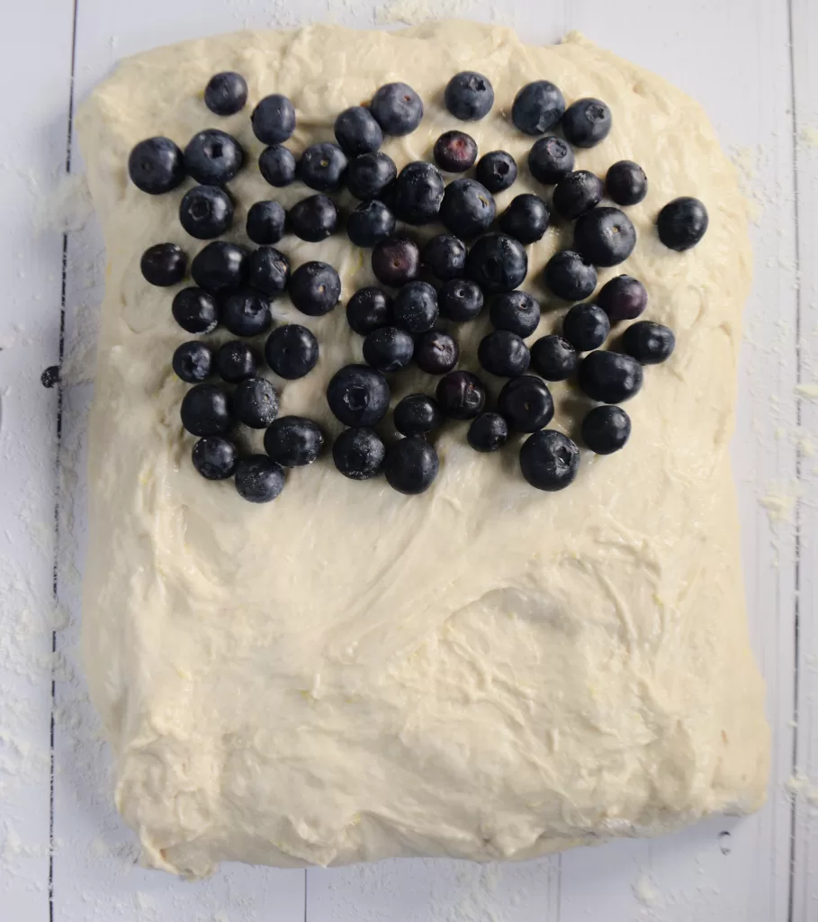 Sourdough folded with blueberries inside on a white countertop for Simple Lemon Blueberry Sweet Sourdough Bread Recipe.