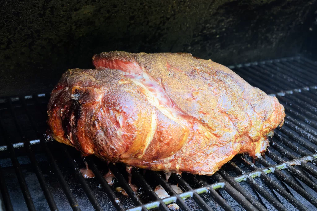 Smoked pork butt on a smoker for Easy Best Slow Smoked Pulled Pork Butt Recipe.