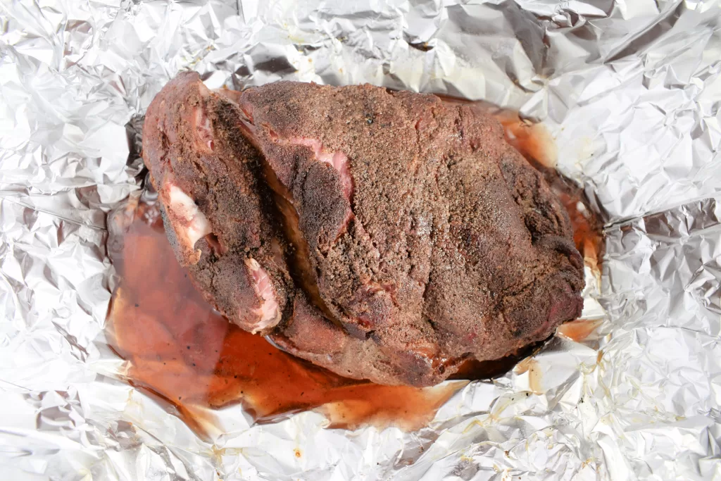Smoked pulled pork on tin foil for Easy Best Slow Smoked Pulled Pork Butt Recipe.