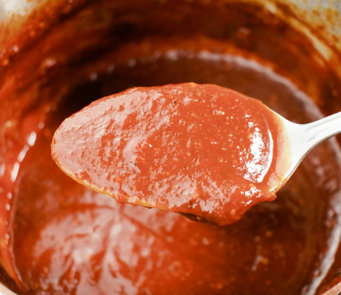 Homemade BBQ sauce on a spoon for The Best Easy Homemade Smoked Meat BBQ Sauce Recipe.
