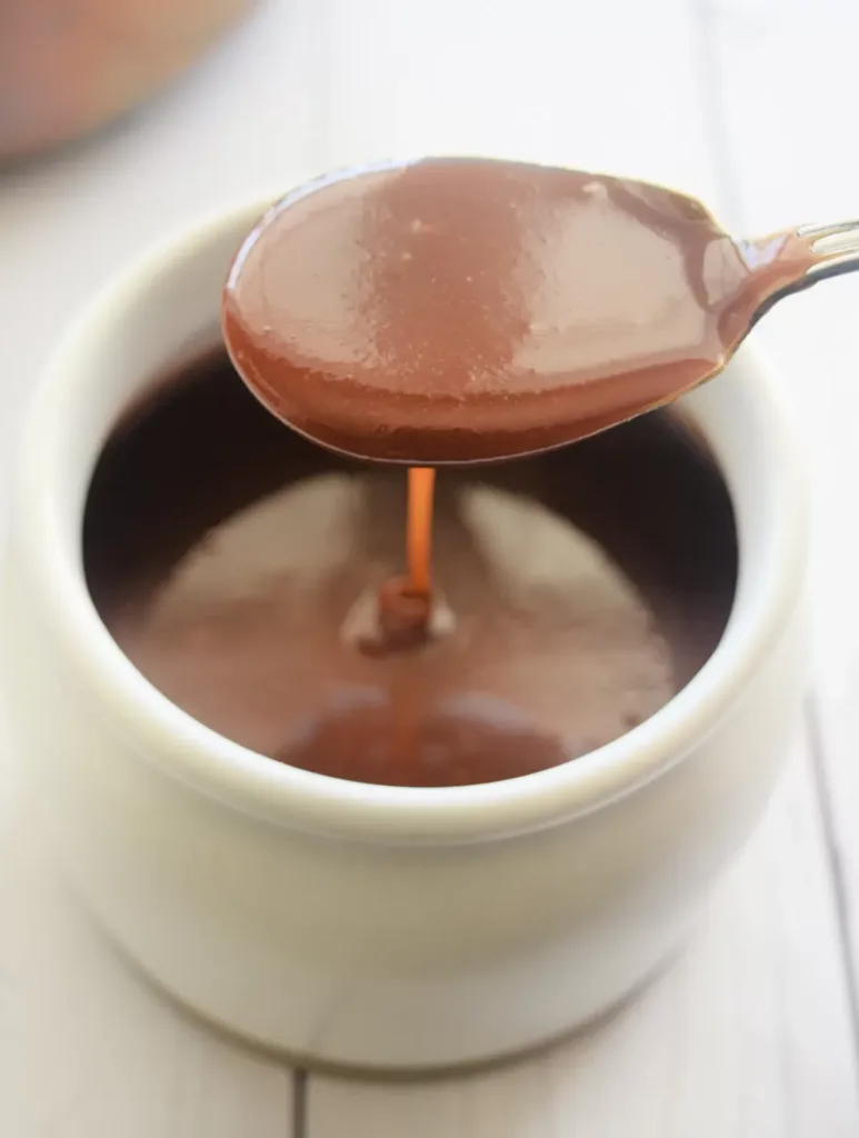 Homemade Soft Caramel Recipe (Without Corn Syrup) with a silver spoon in it on a white countertop.
