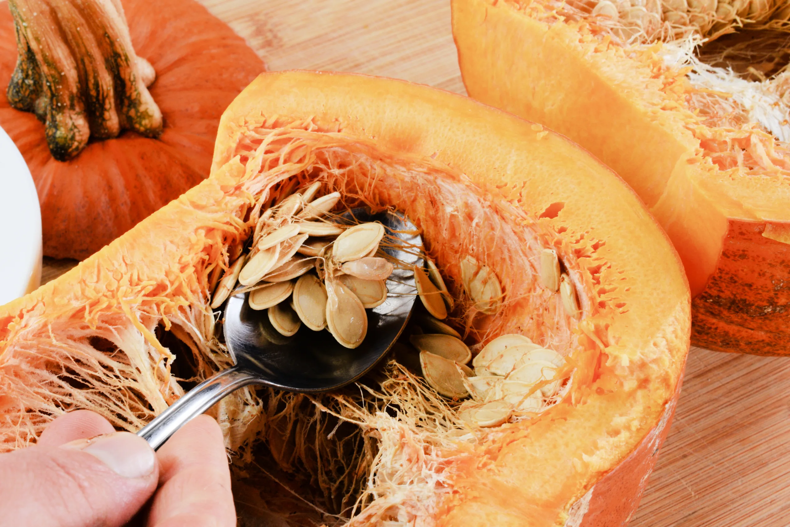 Whole pumpkin being cut and cleaned for How to Roast a Whole Pumpkin to Make Pumpkin Purée.