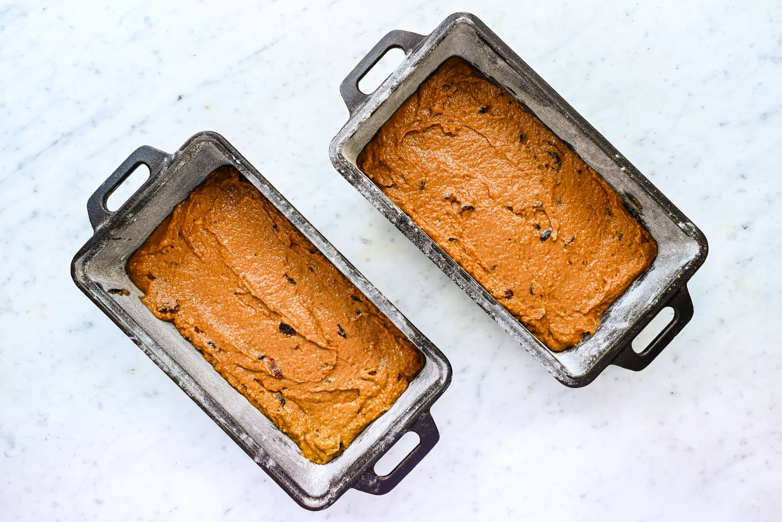 Sourdough pumpkin cranberry quick bread batter divided between two loaf pans.