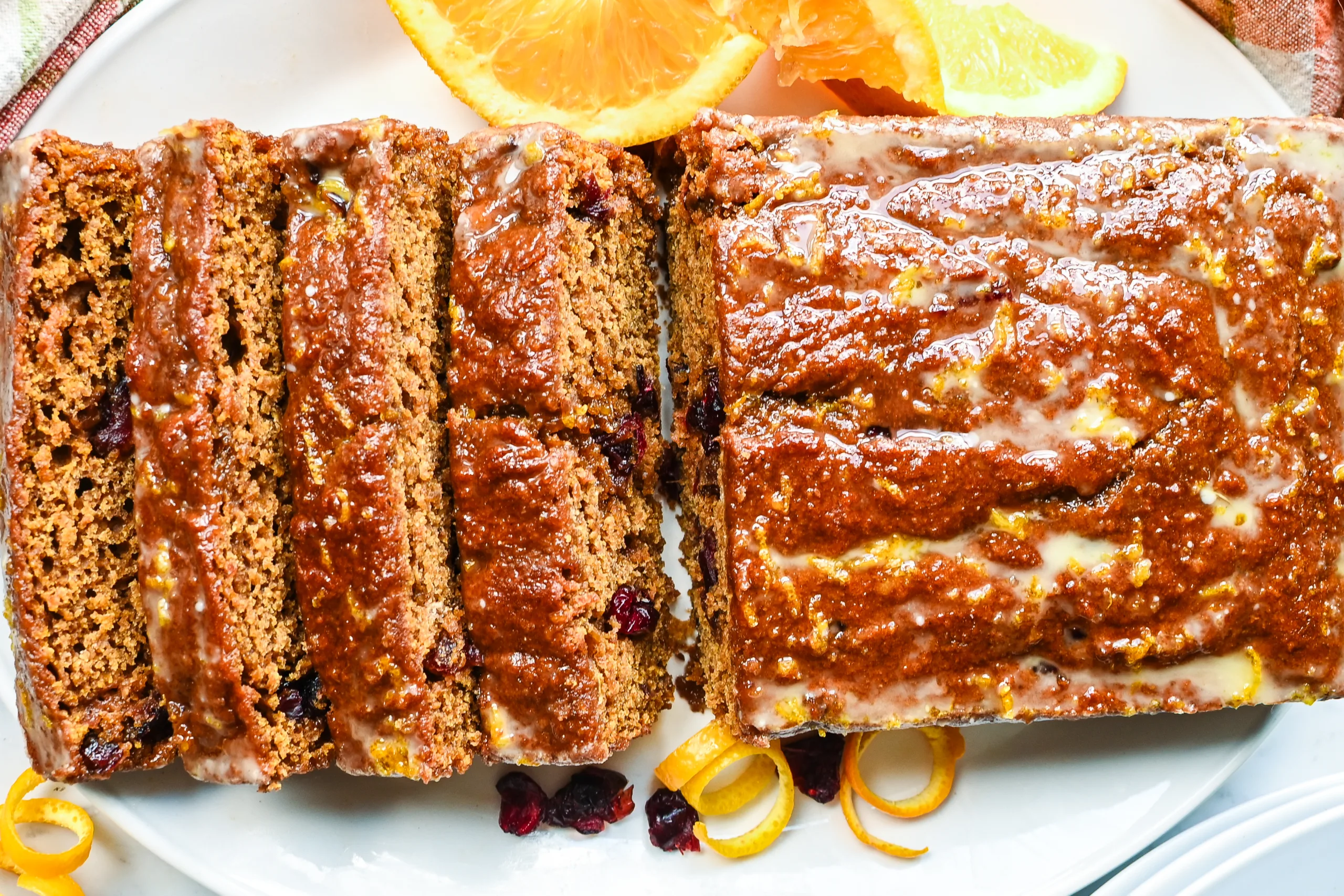 Sliced sourdough pumpkin cranberry quick bread with orange glaze and dried cranberries.