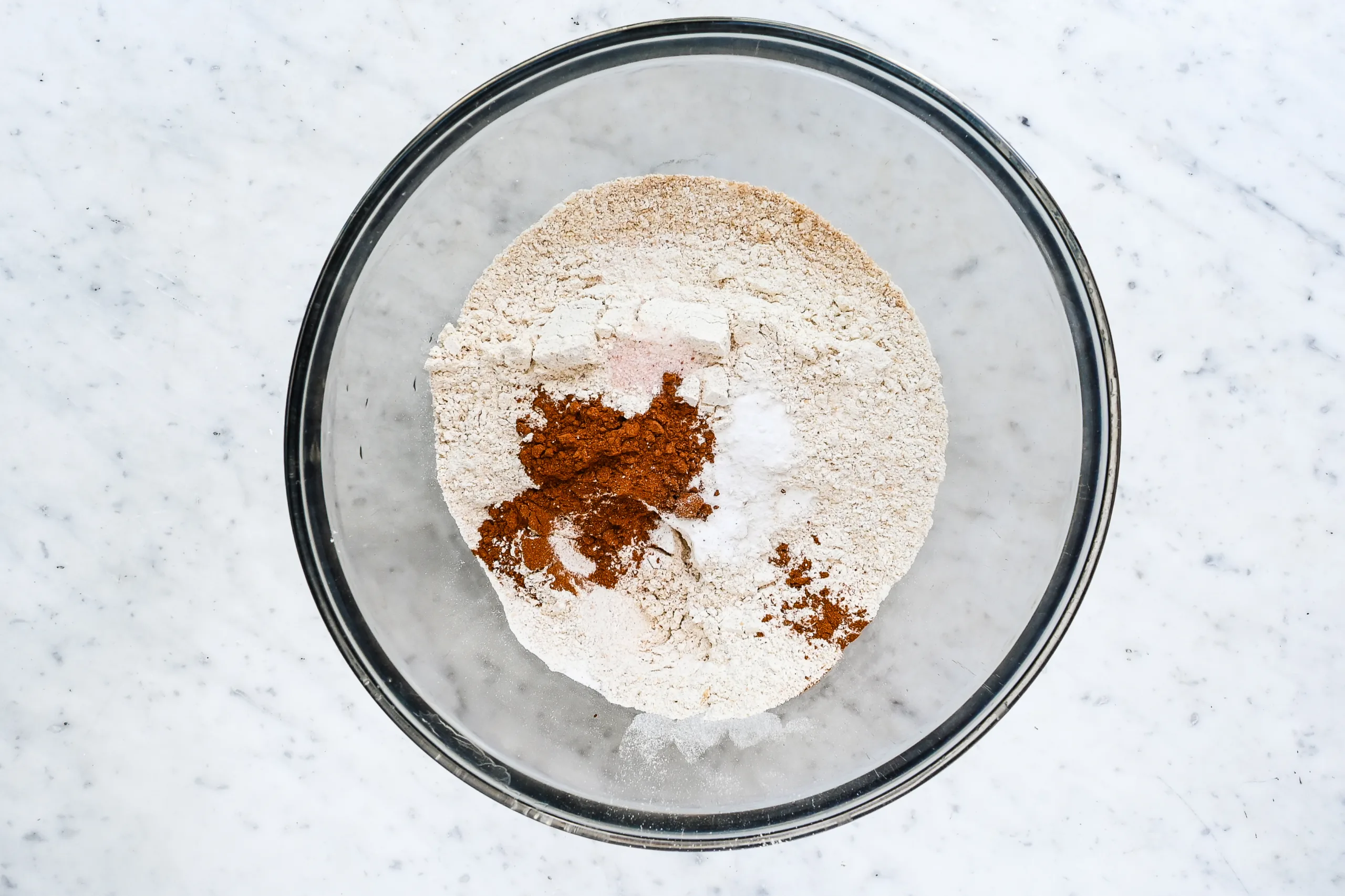 Flour, pumpkin pie spice, baking soda, baking powder, and salt in a glass mixing bowl.