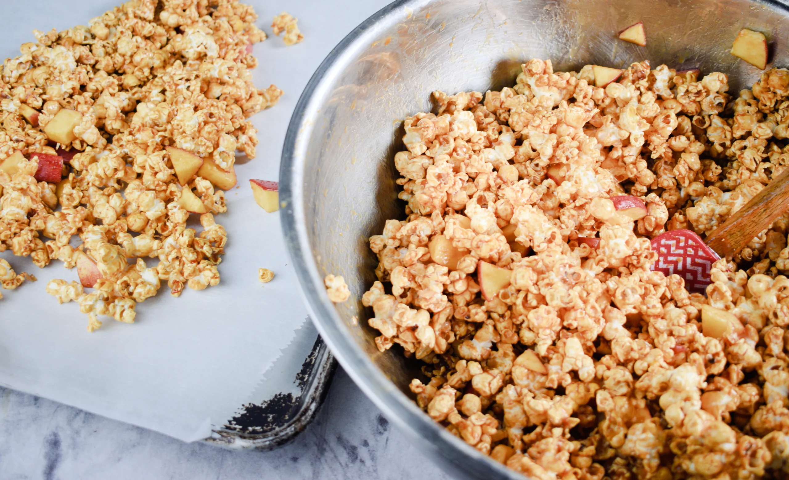 A bowl and cookie sheet full of Homemade Caramel Apple Popcorn Without Corn Syrup.
