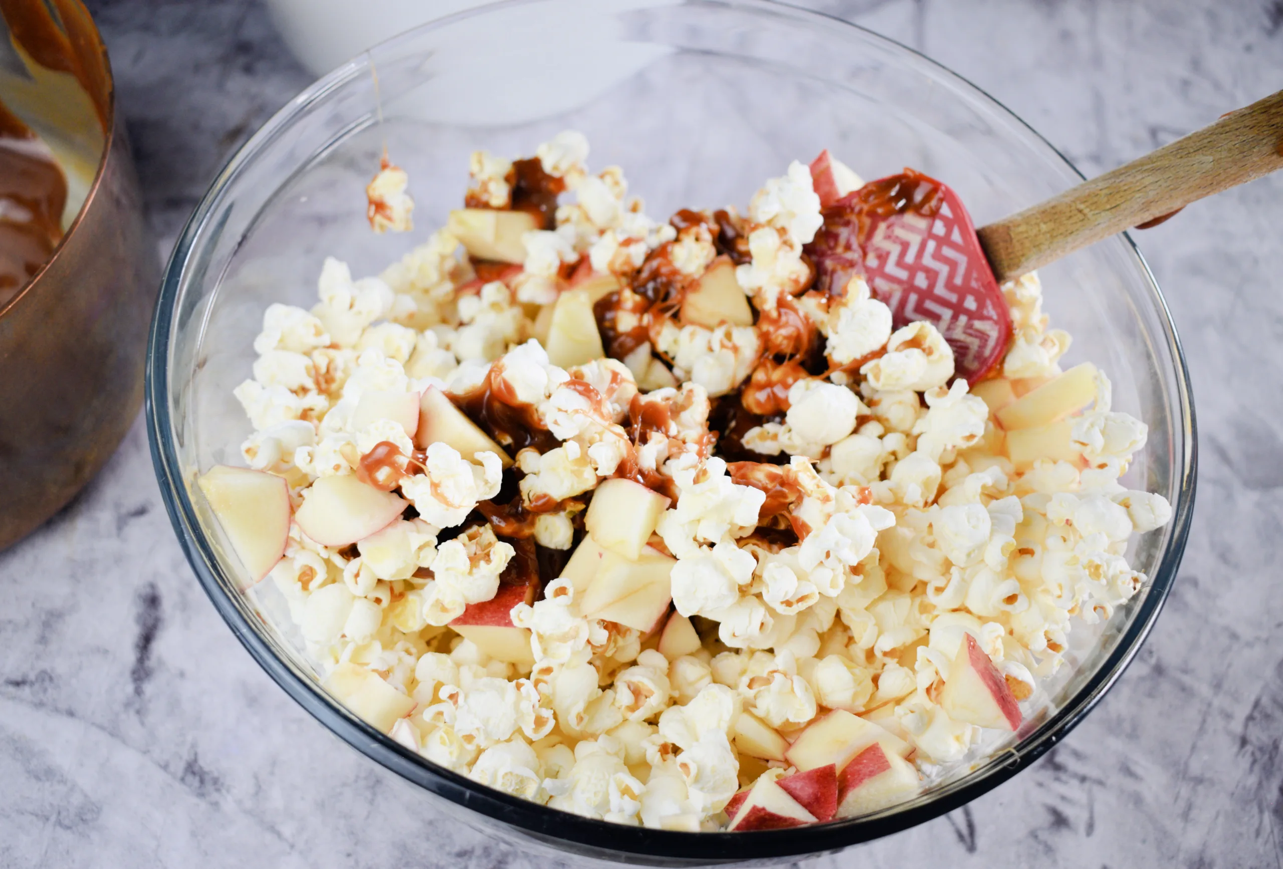 Mixing caramel with popcorn apple mixture for Homemade Caramel Apple Popcorn Without Corn Syrup.