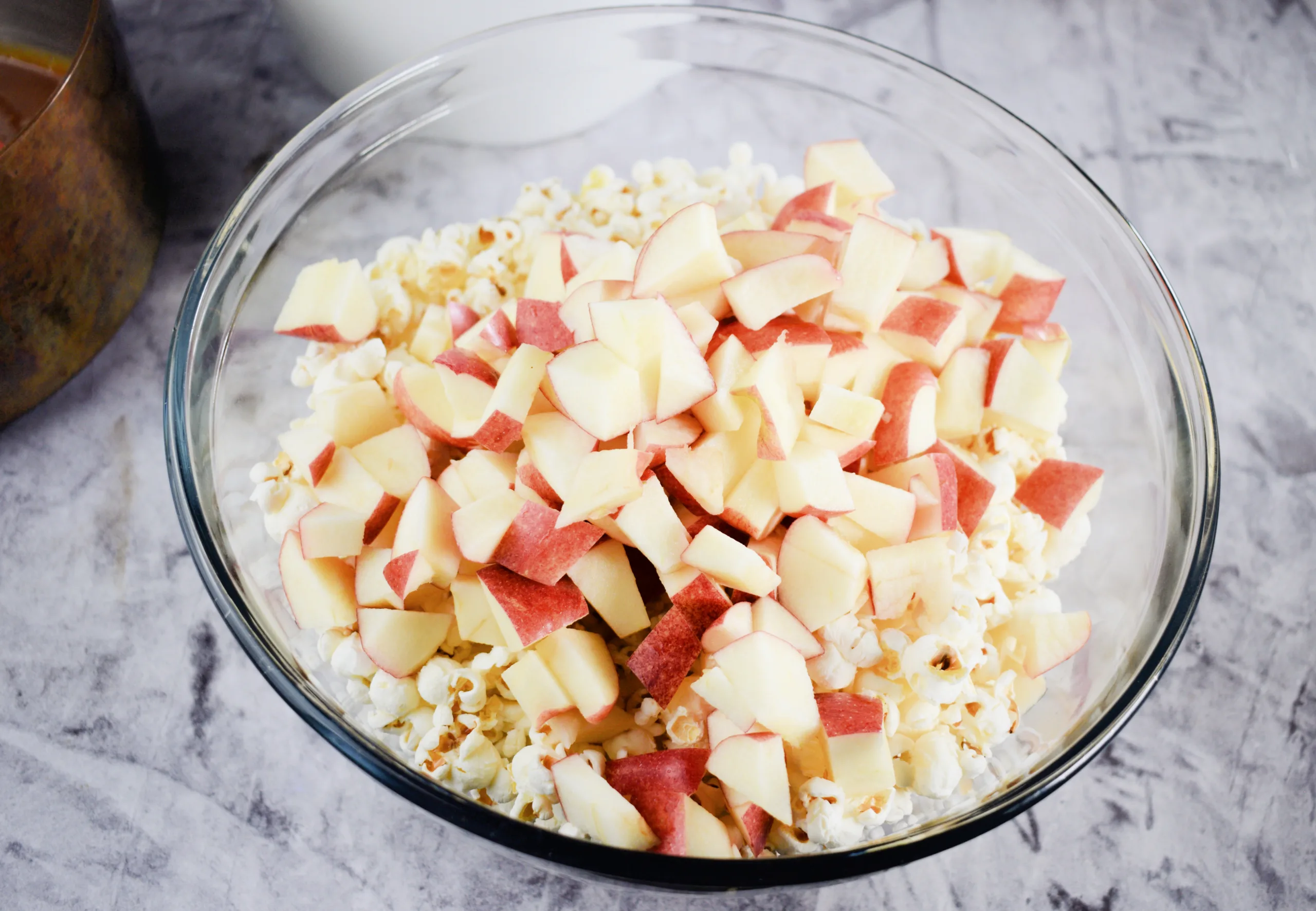 A bowl full of popcorn and apples for Homemade Caramel Apple Popcorn Without Corn Syrup.