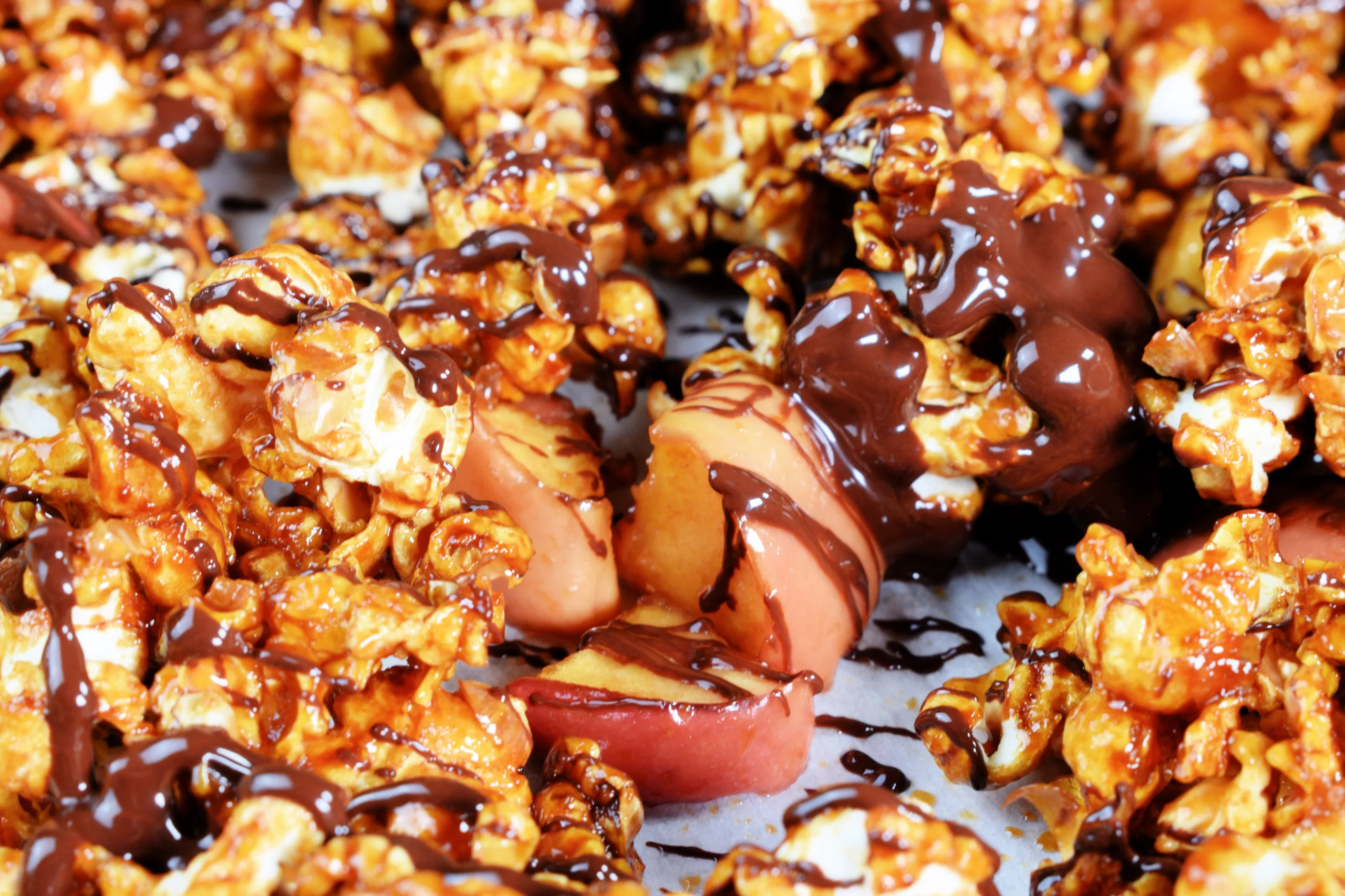 Caramel apple popcorn with chocolate drizzle and apple pieces.