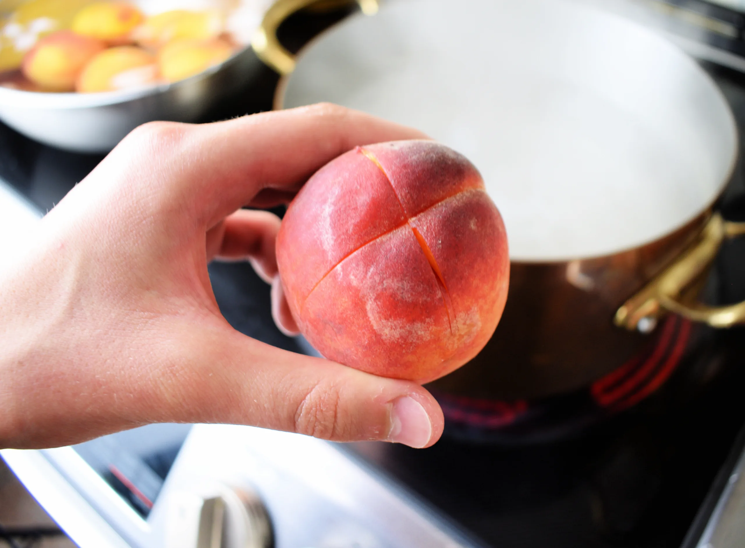 Fresh peach scored with an X before blanching and peeling.