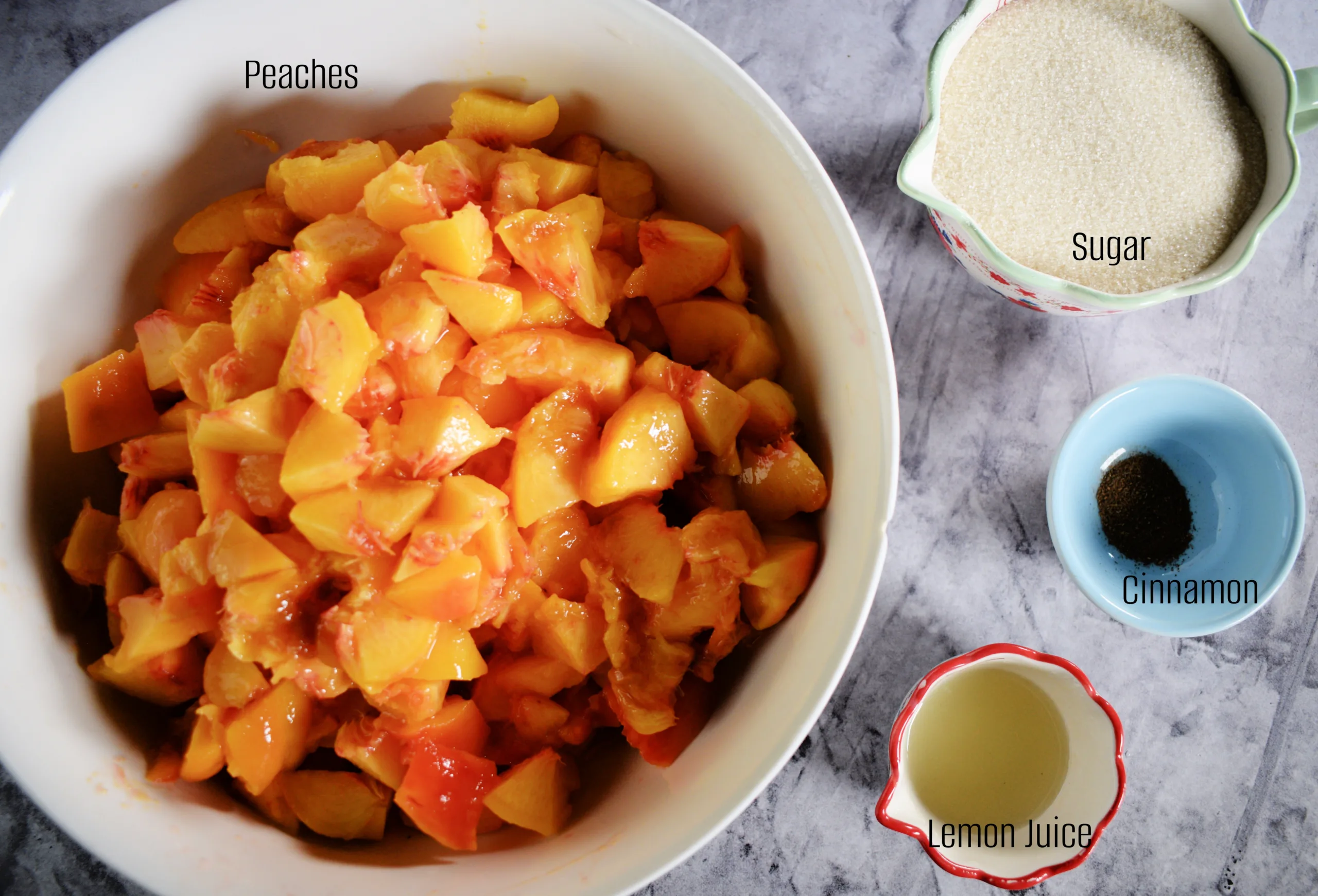 Labeled ingredients for peach jam with chopped peaches, sugar, cinnamon, and lemon juice.