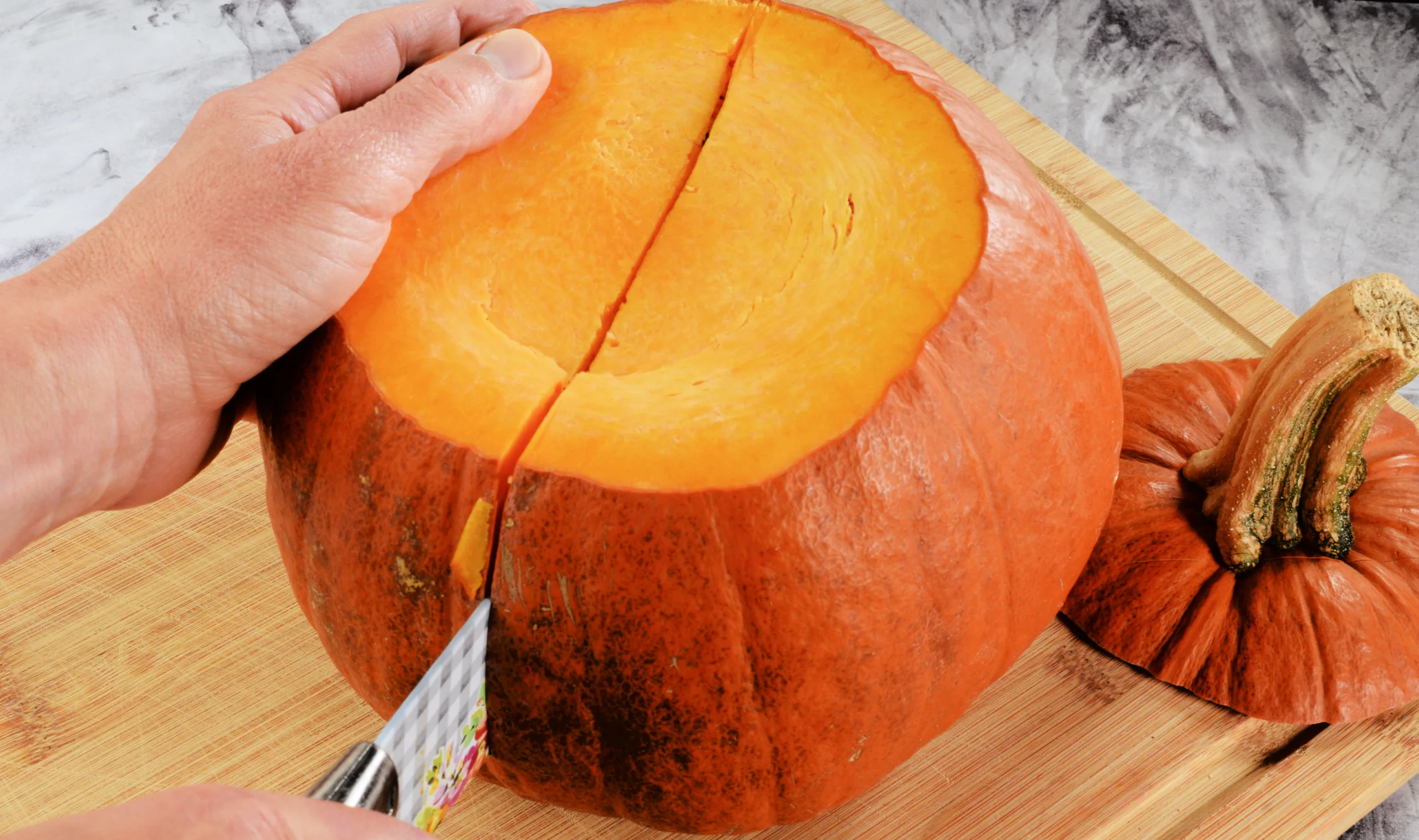 Cutting the whole pumpkin with a sharp knife in half before removing the seeds.
