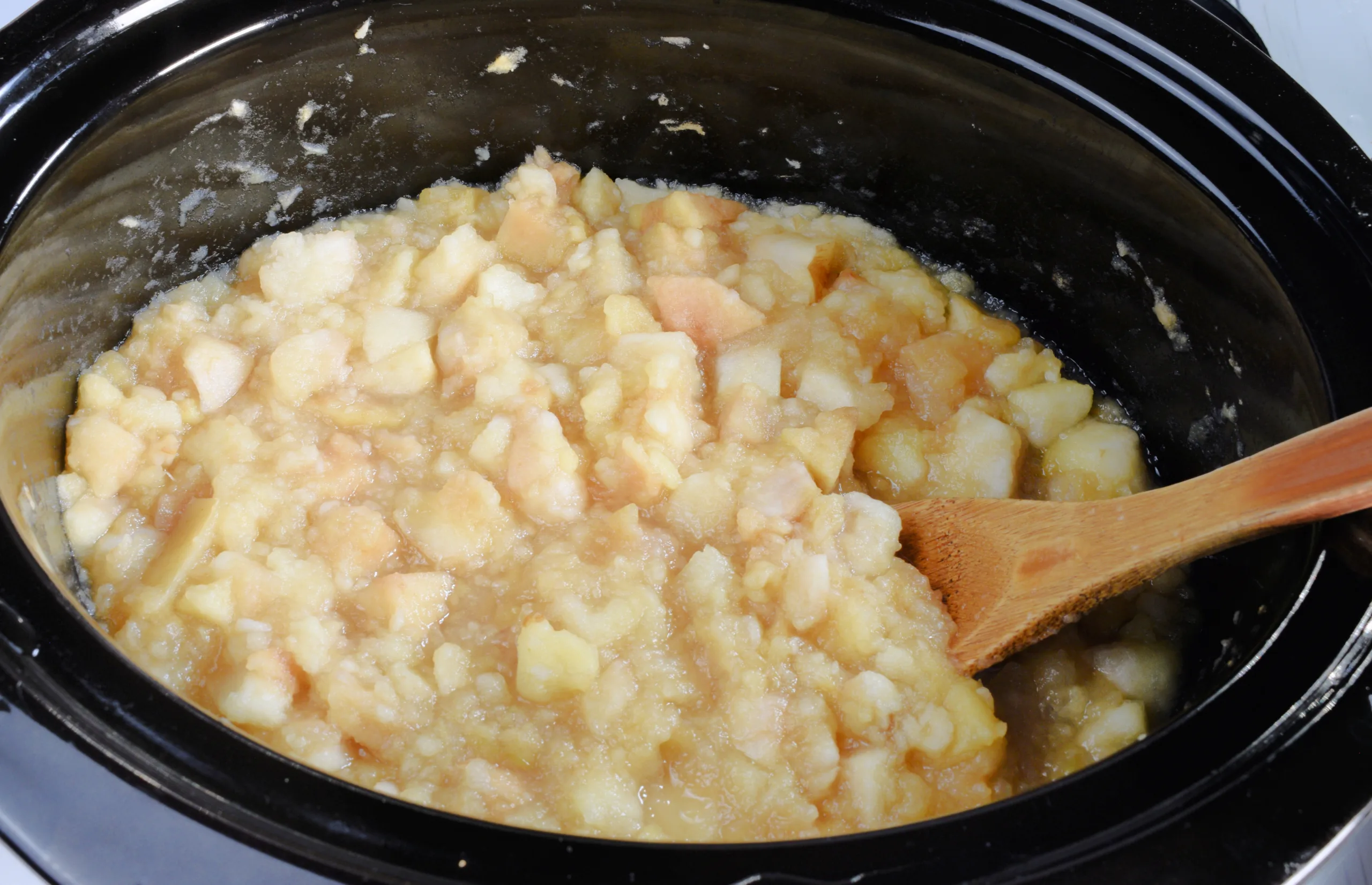Cooked apples stirred in a slow cooker before blending into apple butter.