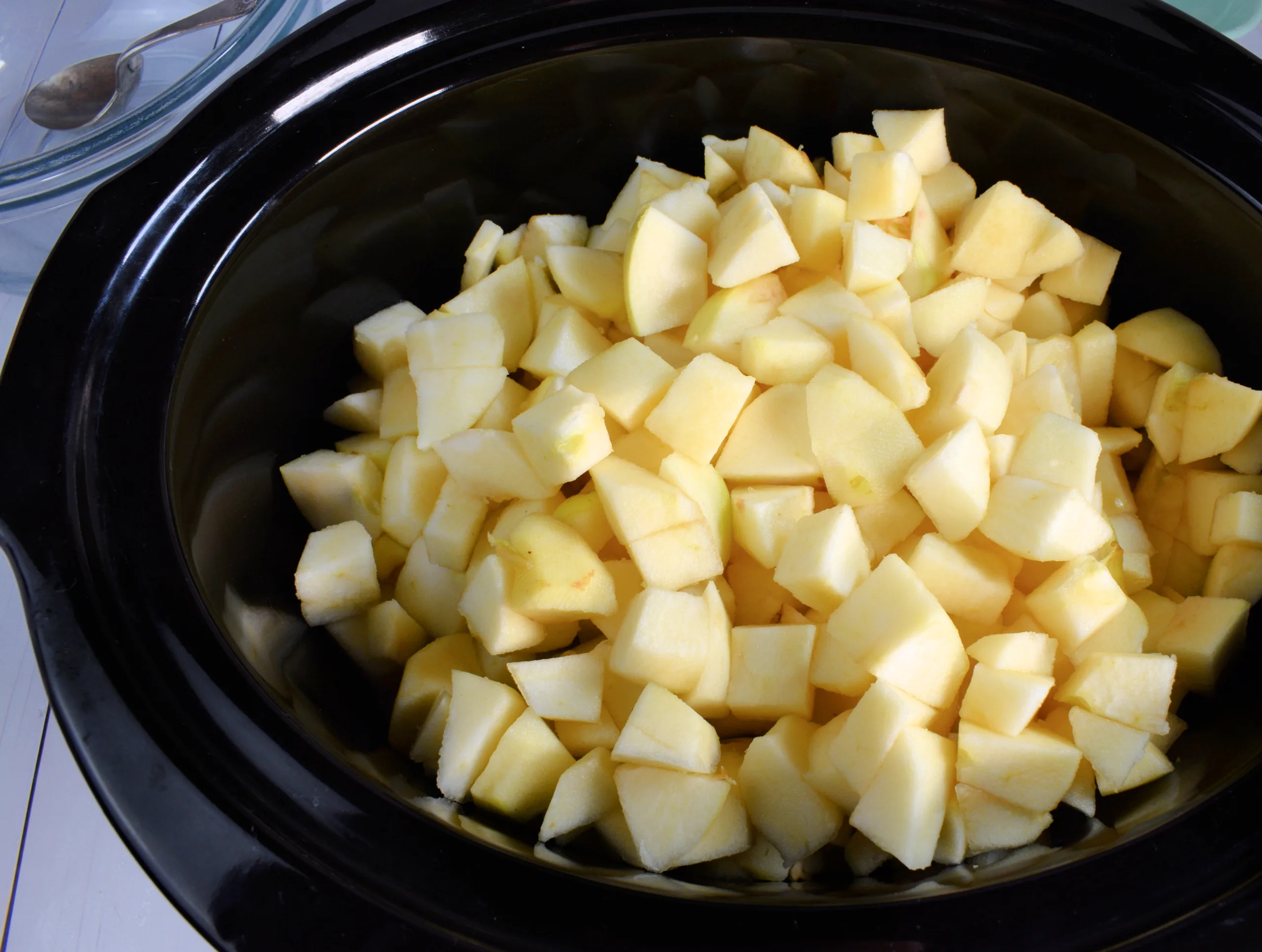 Peeled and chopped apples added to a slow cooker for apple butter.