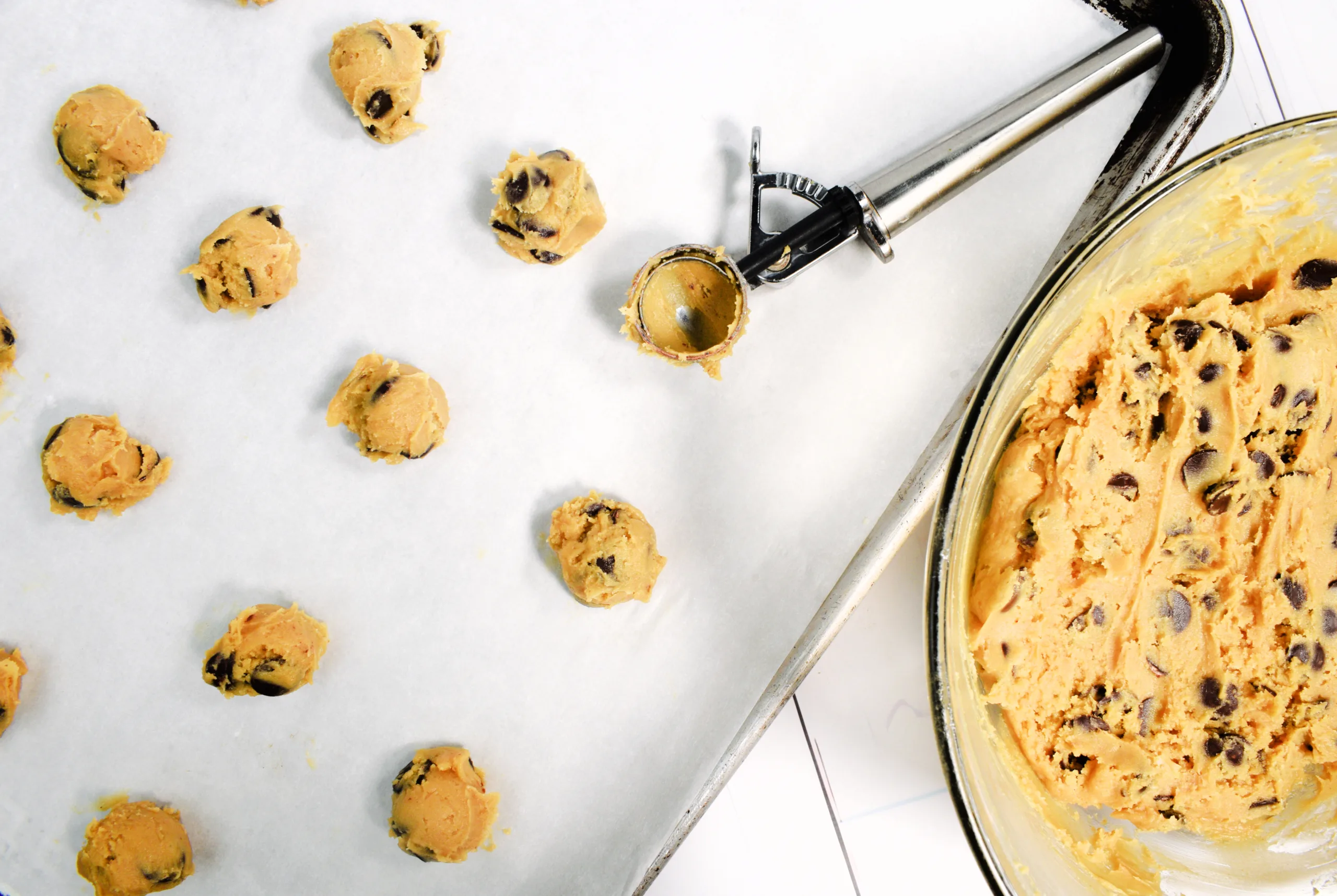 Using a cookie scoop and placing dough on a cookie sheet for The Best Sourdough Chocolate Chip Cookies Recipe.