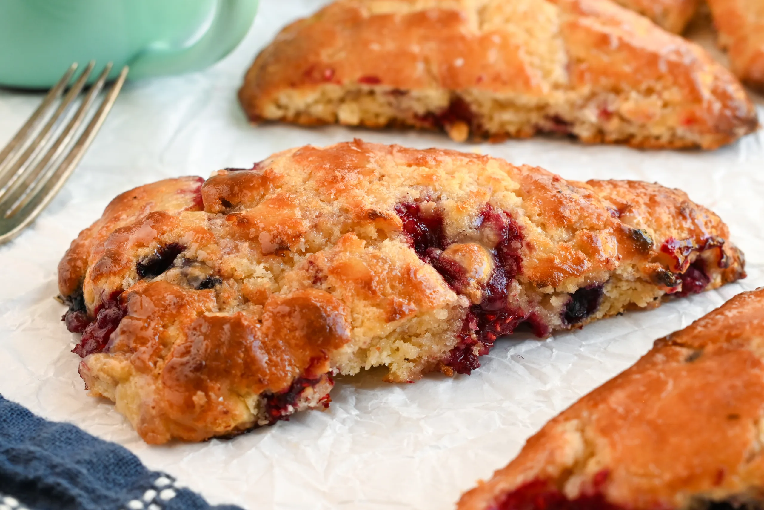 Moist, tender sourdough berry scone with juicy raspberries and blueberries, glistening with honey glaze.