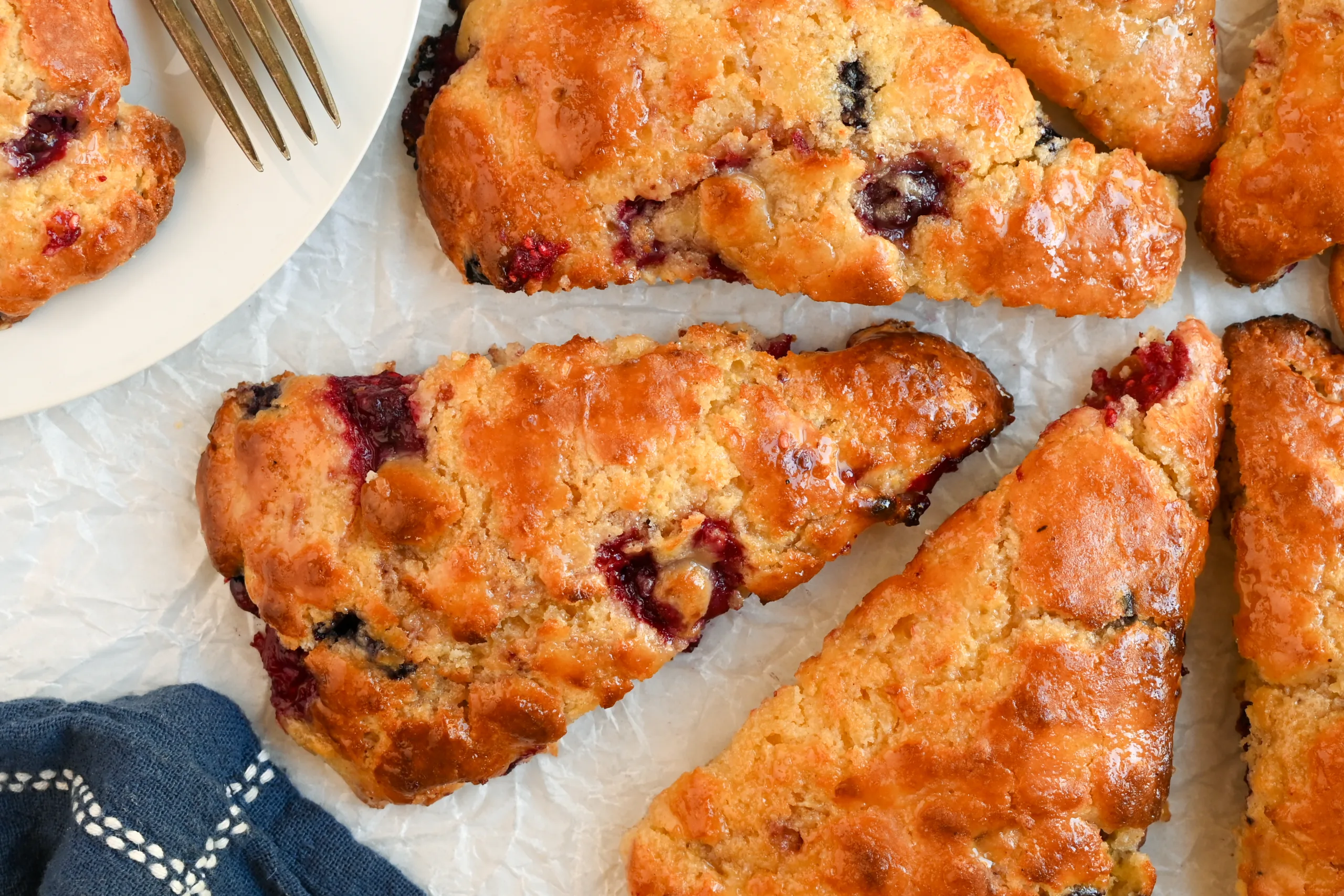 Moist, tender sourdough berry scone with juicy raspberries and blueberries, glistening with honey glaze.