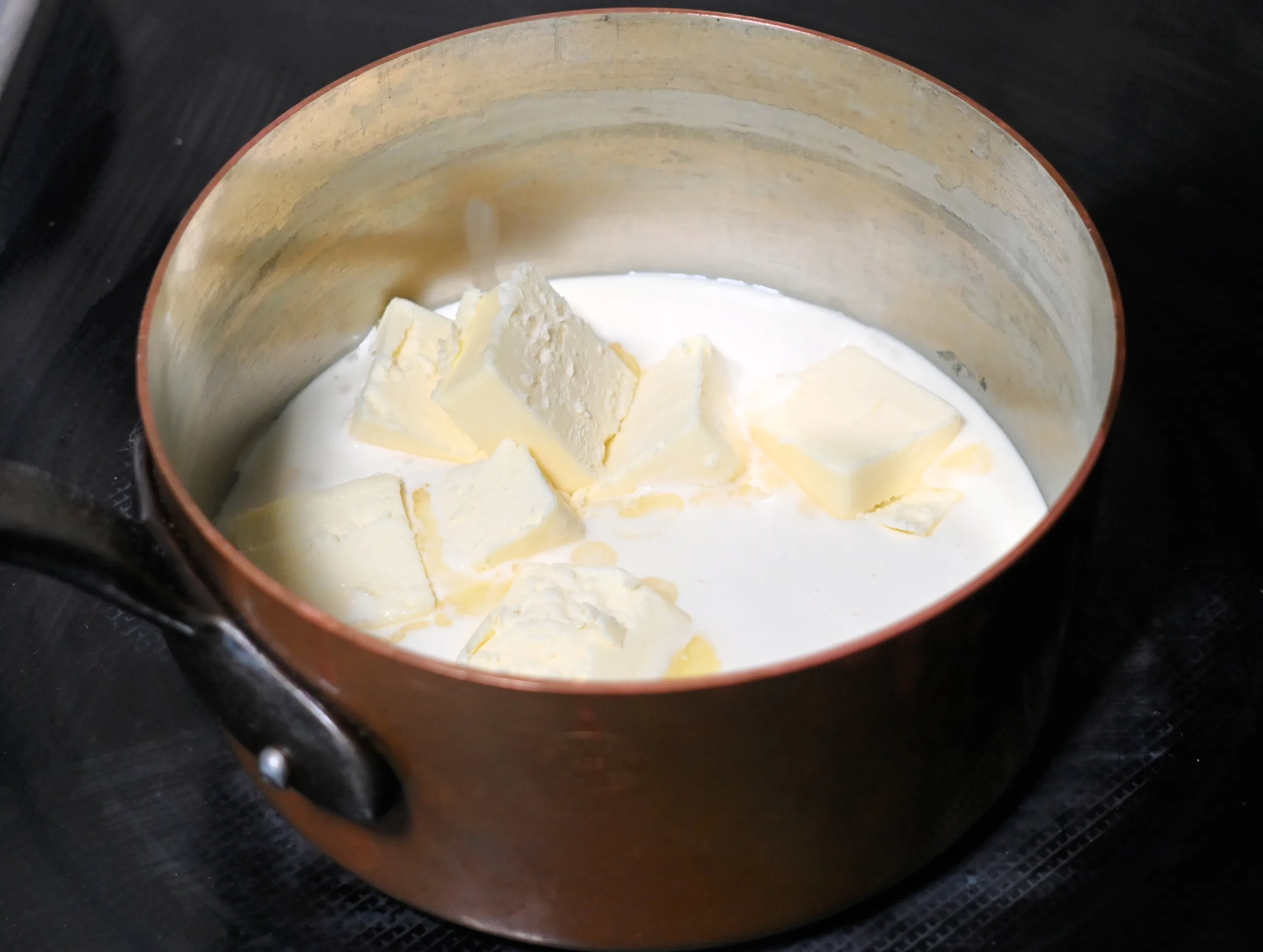 Heavy cream and butter warming in a saucepan for homemade chewy caramels.
