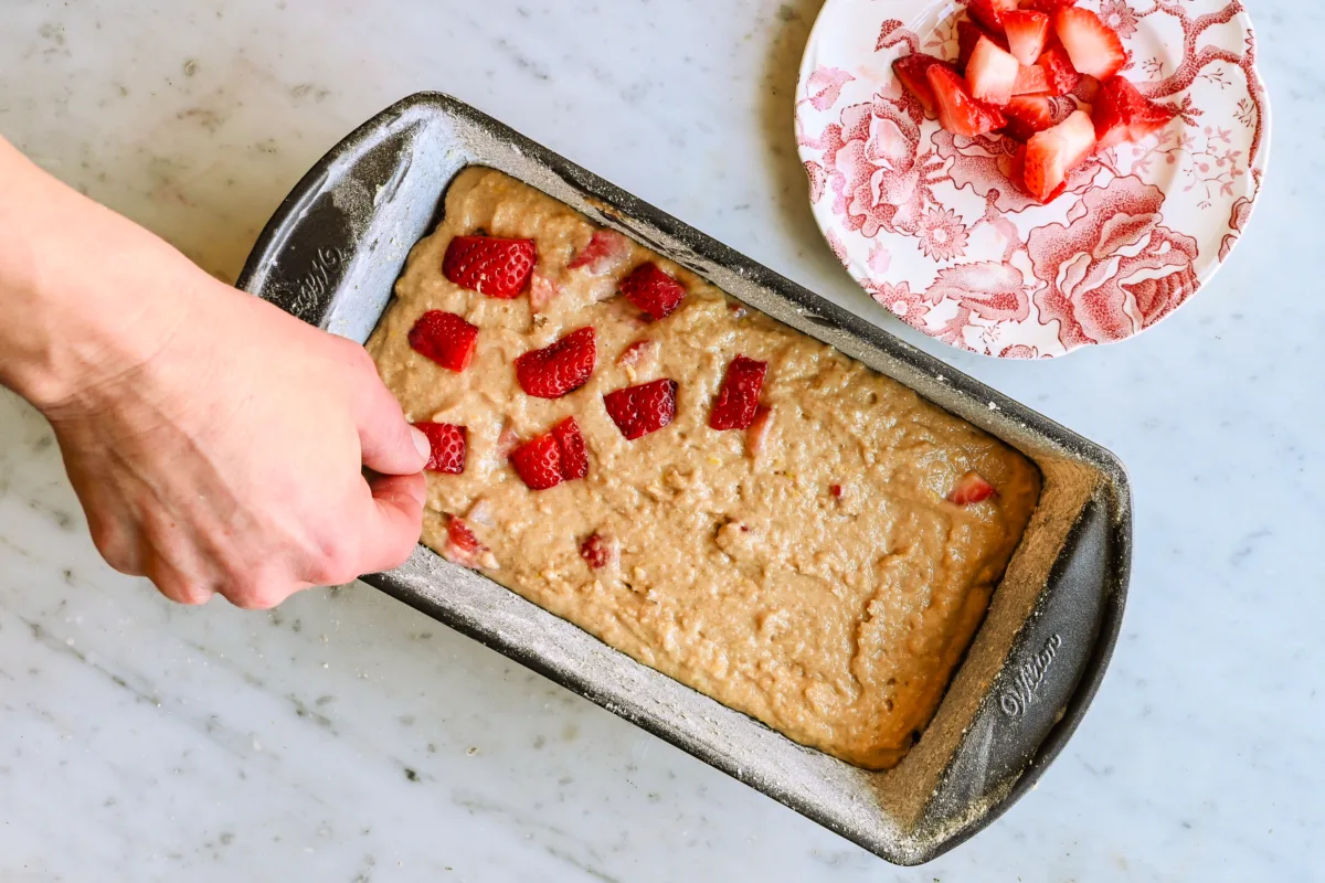 Placing strawberries on top of the strawberry quick bread dough.