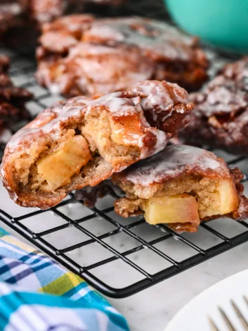 Close-up of a sliced apple fritter showing soft apple chunks, warm spices, and a shiny glaze.
