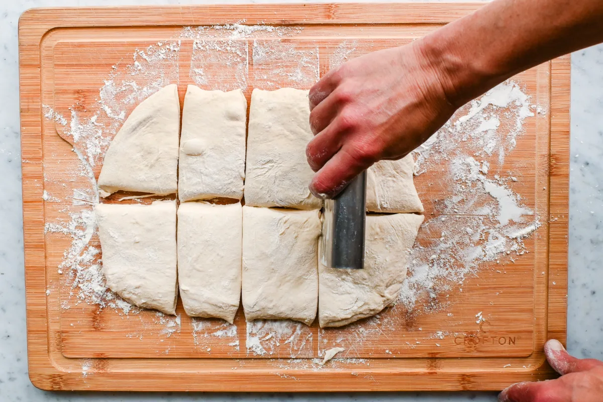 Using a bench scraper, divide the dough into two, then divide each half into four equal pieces to form 8 small rectangles. Then, lightly shape each piece into a rectangle.