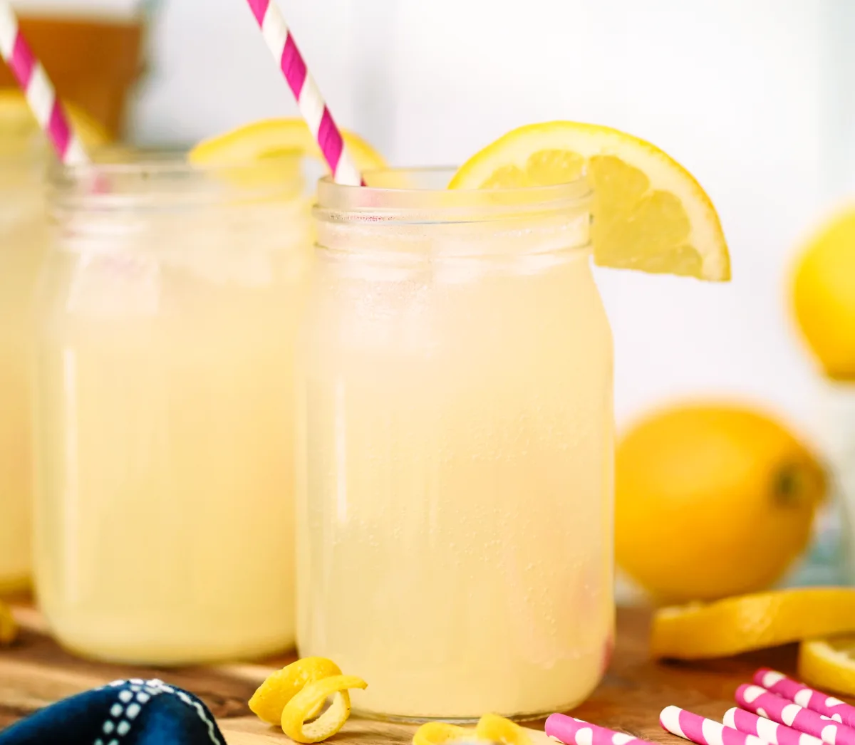 Homemade lacto-fermented lemonade served in mason jars with lemon slices and pink paper straws, a refreshing probiotic soda made with real lemons.