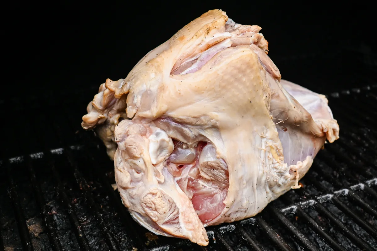 Uncooked turkey breast on smoker grill at the start of the smoking process