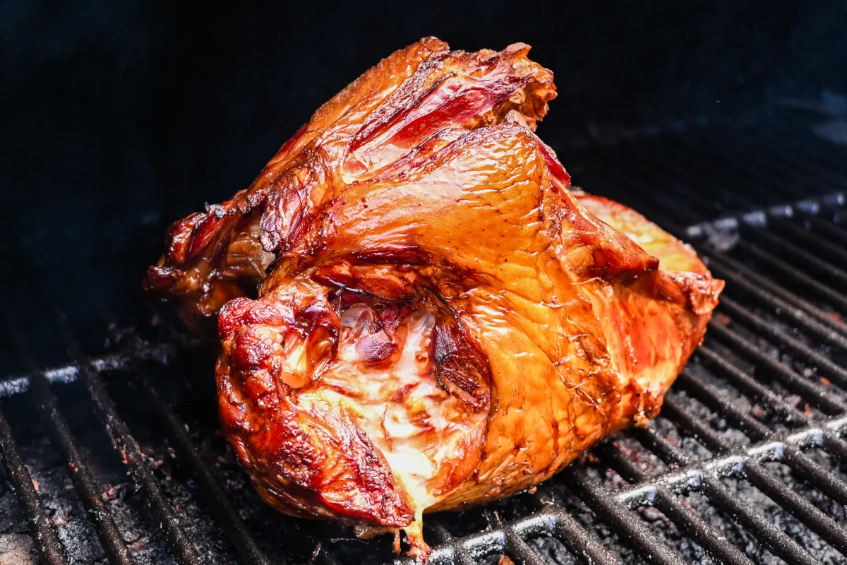 Perfectly smoked turkey breast with golden, crispy skin on smoker grill