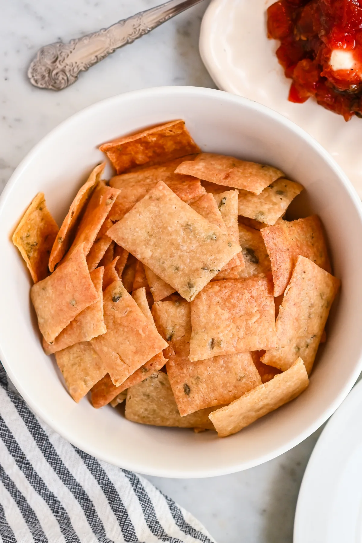 Golden brown homemade sourdough discard crackers in a bowl—perfect for charcuterie boards or as a substitute for store-bought crackers.