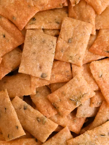 Golden brown homemade sourdough discard crackers in a bowl—perfect for charcuterie boards or as a substitute for store-bought crackers.