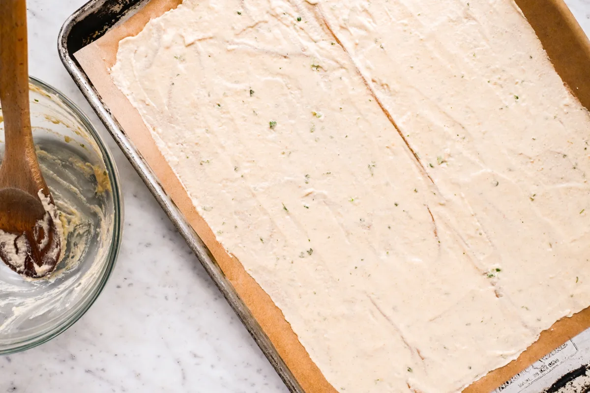 Slicing freshly baked thin and crispy sourdough crackers with a pastry cutter—homemade crackers perfect for charcuterie boards.