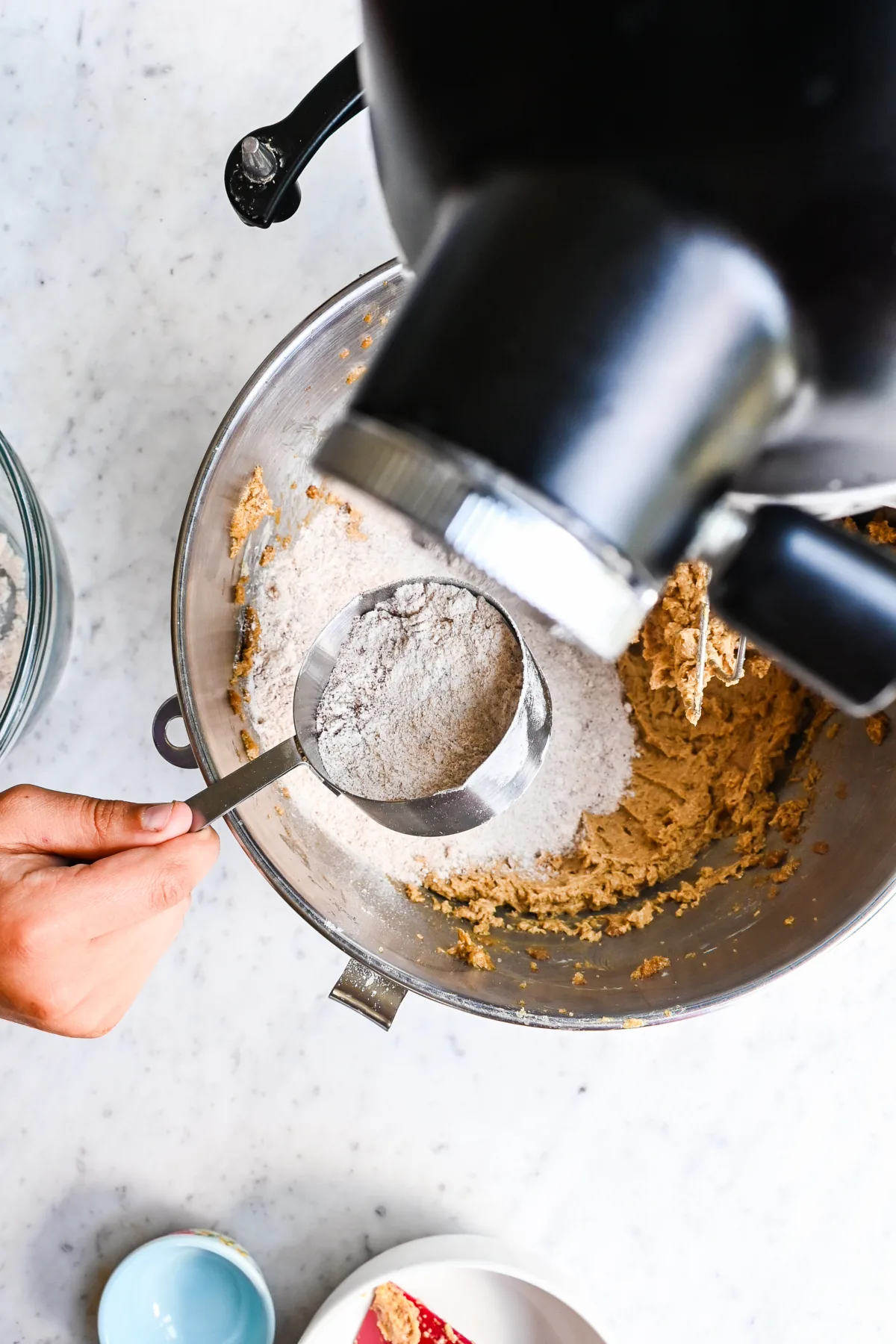 Mixing dry ingredients including fresh milled flour, cinnamon, and salt in a glass bowl for oatmeal raisin cookie dough.
