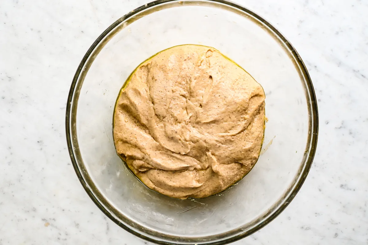 A glass bowl of fully mixed sourdough apple cider donut batter, smooth and spiced, and ready to rest.