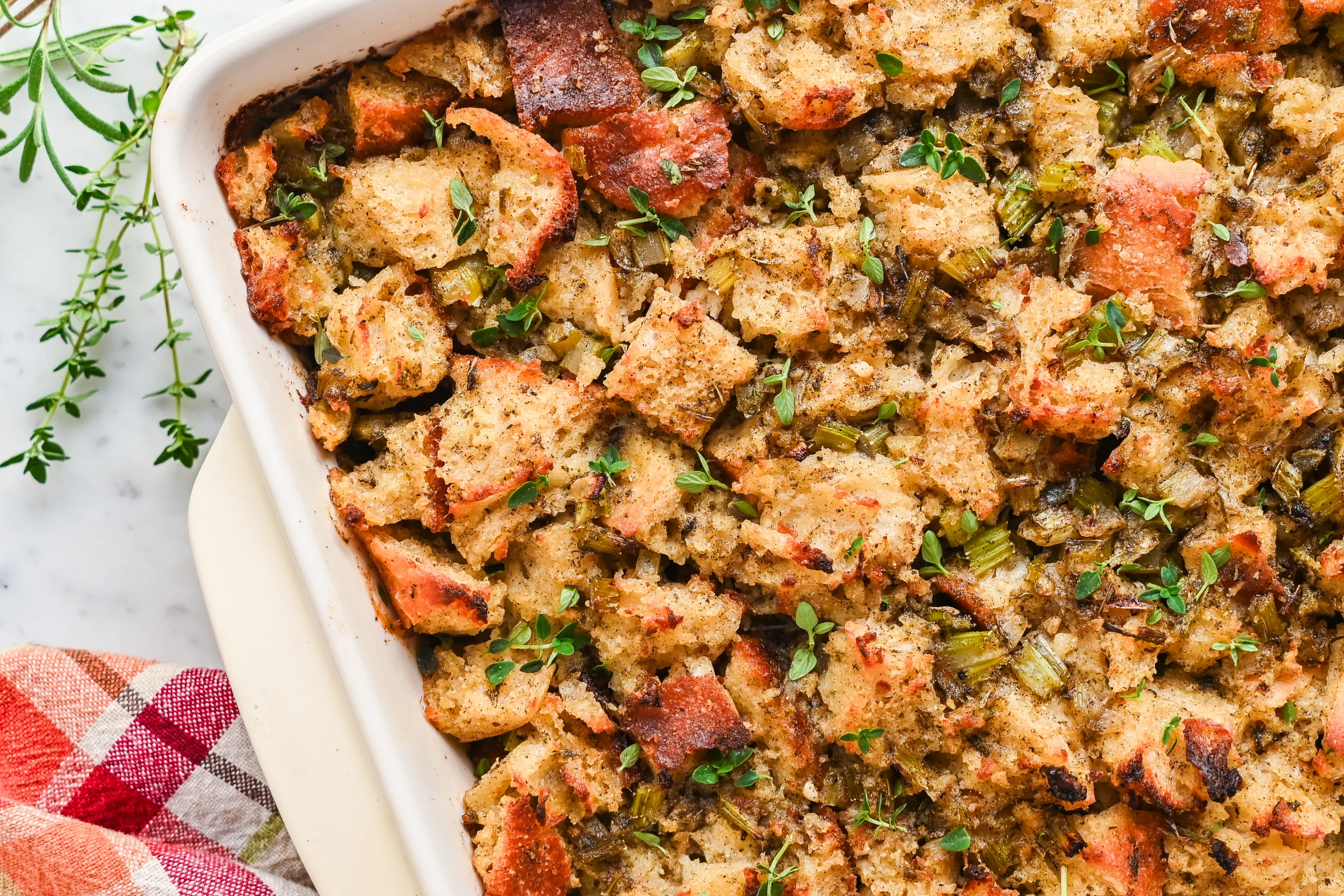 Sourdough stuffing mixture in baking dish topped with pieces of butter before baking for a golden brown crispy top.