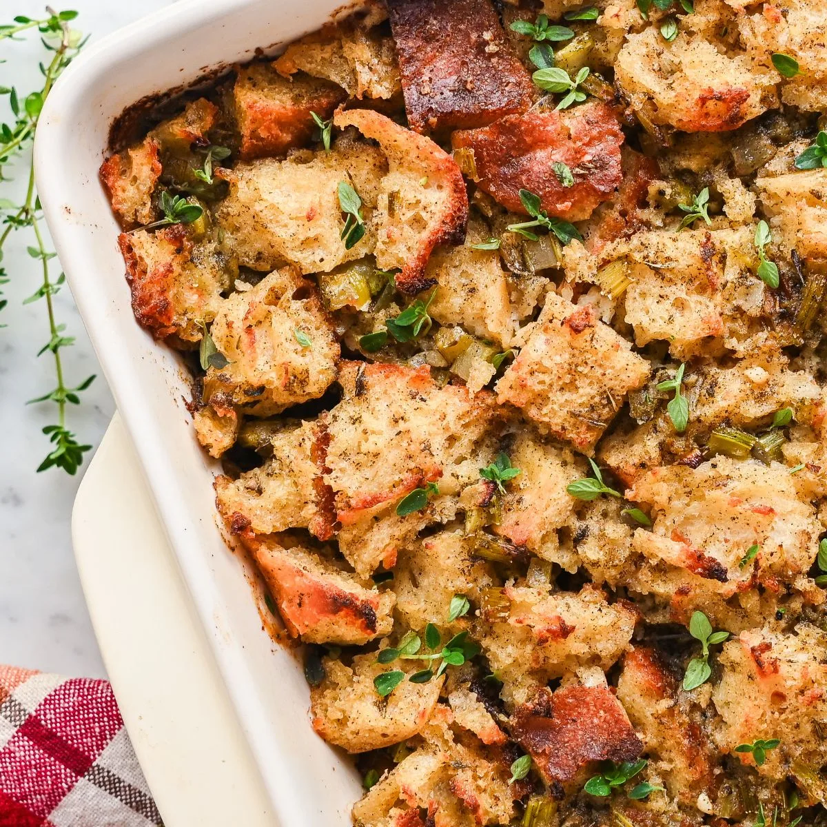 Sourdough stuffing mixture in baking dish topped with pieces of butter before baking for a golden brown crispy top.