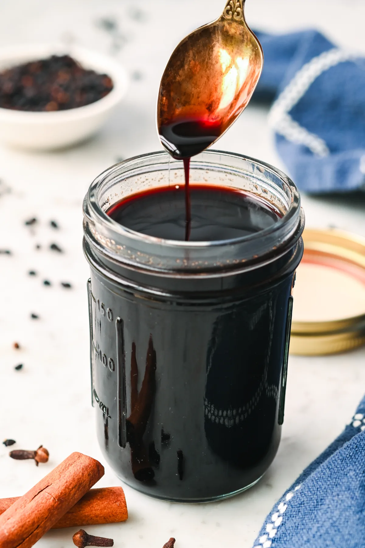 Glass jar filled with dark elderberry syrup and a spoon, ready for immune-boosting use.