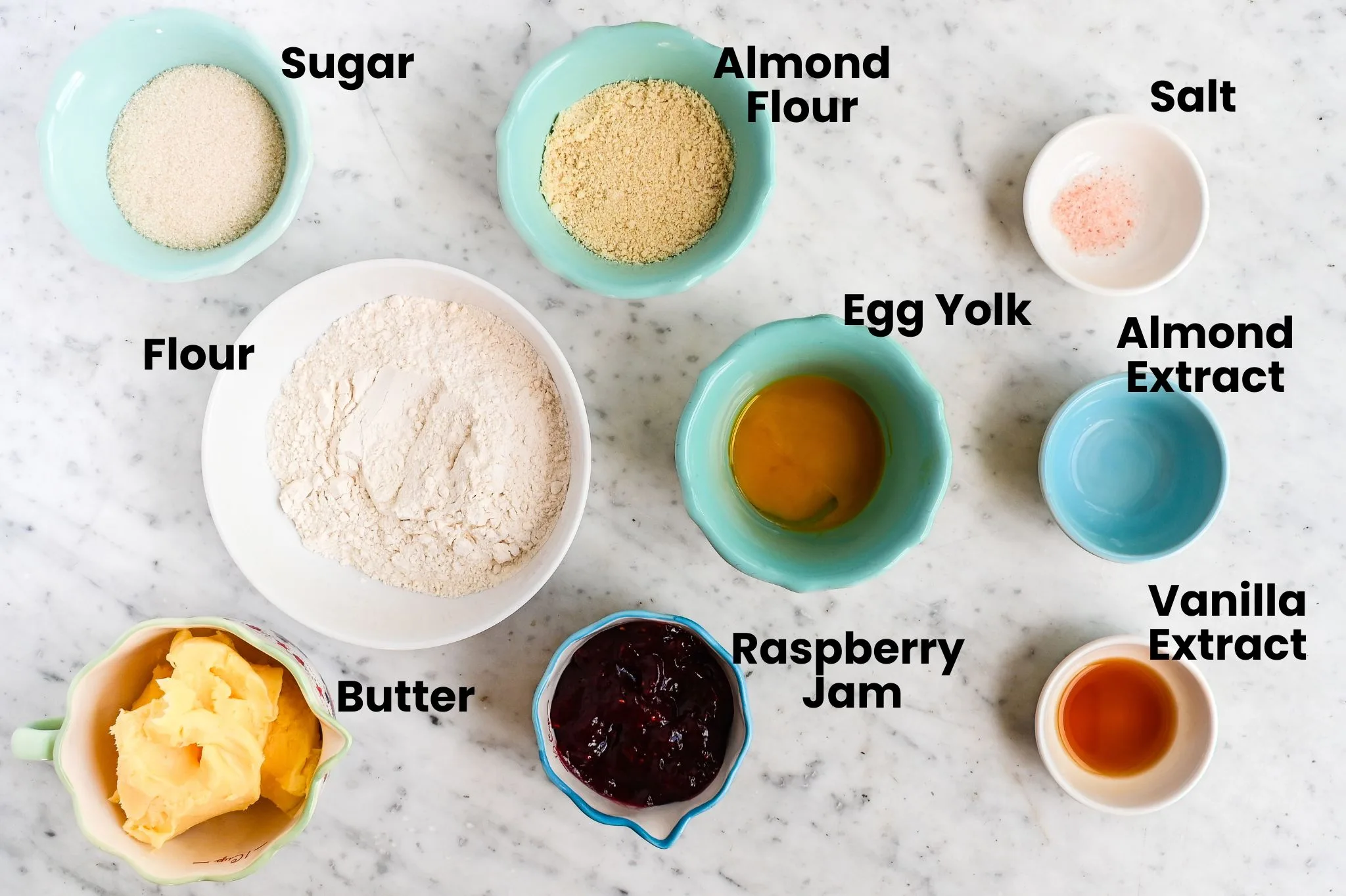 Ingredients for raspberry thumbprint cookies measured into bowls on marble counter