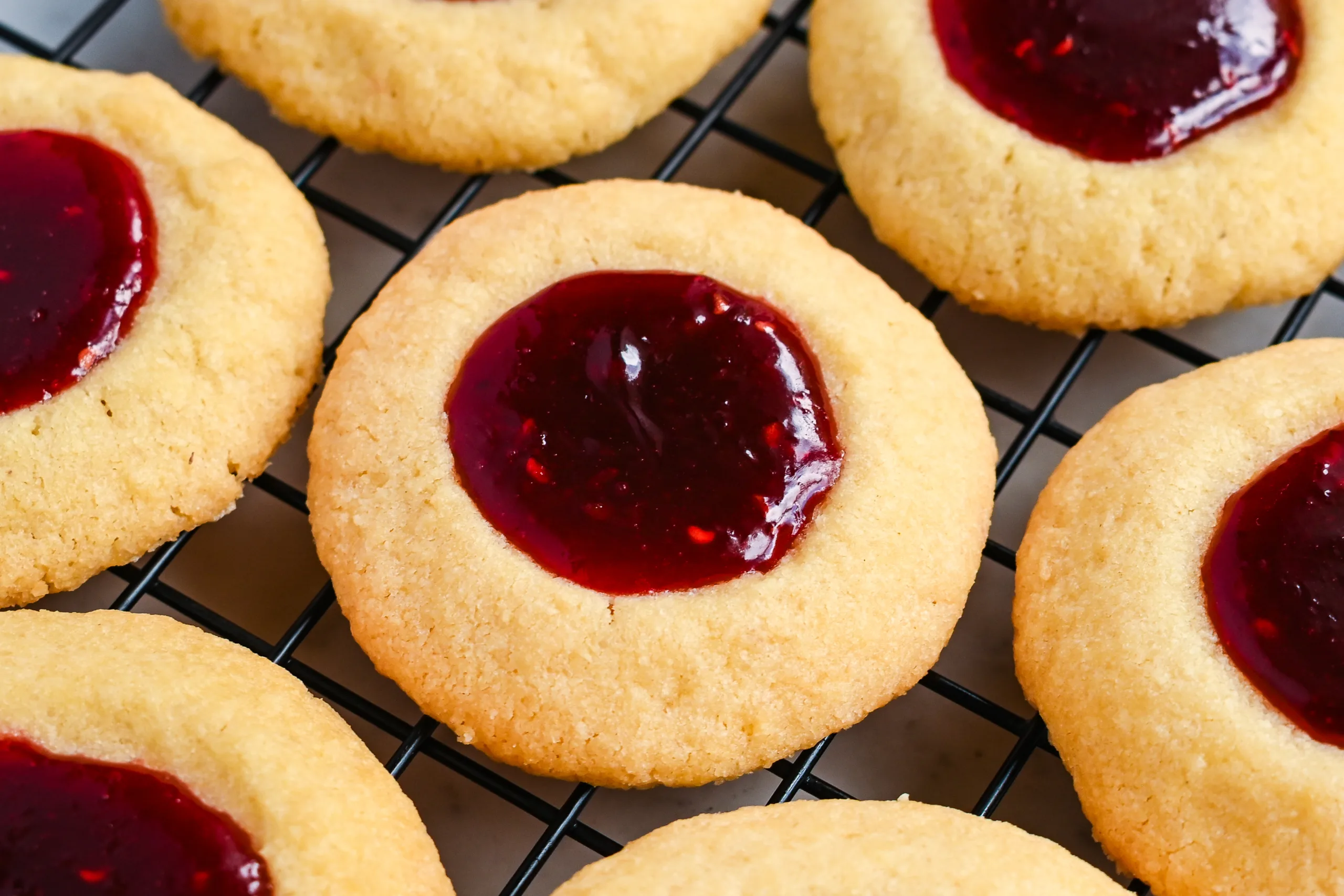 Close up of raspberry thumbprint cookies on a cookie rack.