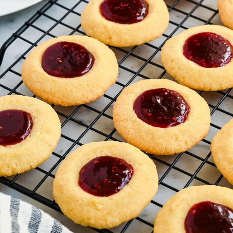 Raspberry thumbprint cookies cooling on a wire rack after baking